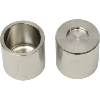 Two cylindrical metallic brake caliper pistons with a smooth, shiny silver finish; one shows a hollow interior, the other a.