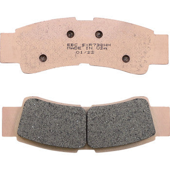 Set of rectangular motorcycle brake pads with copper-colored backing plates and textured gray friction surfaces.