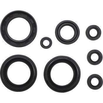 Seven black rubber oil seals from the Suzuki Oil Seal Set by Moose Offroad are neatly arranged on a white background. The circular seals, each a different size, are laid out in an organized, slightly staggered pattern.