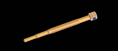 A golden, cylindrical alloy steel Rzr Pro Xp Clutch Puller by Trinity Racing, featuring a hexagonal nut at one end, is displayed on a black background. This precision tool is made in the U.S.A.