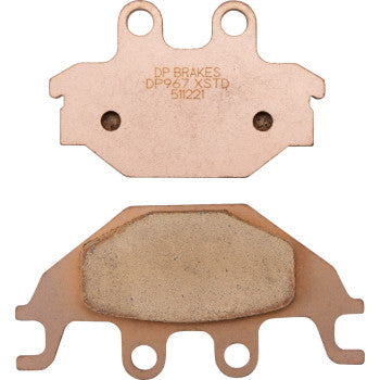 Two Kymco Standard Brake Pads by DP Brakes are shown—one with the engraved DP967/XS TD 51121 label and the other showing its textured sintered friction material, making them ideal for ATV use.