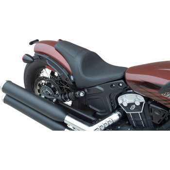 A close-up side view of the 3 / 4 Solo Seat - Black - Smooth by Drag Specialties, featuring black solar-reflective leather, rear wheel, and dual exhaust pipes on a red and black cafe-racer motorcycle.