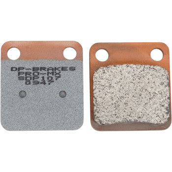 Two Pro MX Sintered Brake Pads by DP Brakes are shown side by side: one has printed text and a smooth gray finish, while the other reveals a textured, worn braking surface. Both pads feature two circular holes at the top.