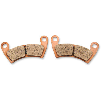 Pair of curved copper-colored metal brake pads with textured beige friction surfaces and mounting holes on each end.