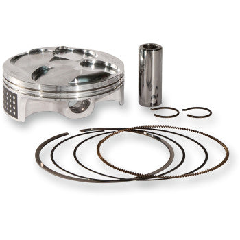 Silver metallic piston with matching wrist pin, two small black circlips, and four black piston rings arranged in front on.