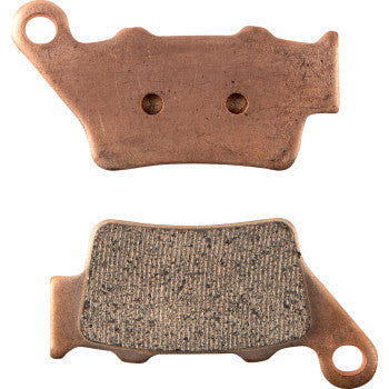 Two copper-colored Sintered Brake Pads by Drag Specialties: one displays its textured friction surface, the other shows the smooth back. Both have holes and notched ends for easy attachment.