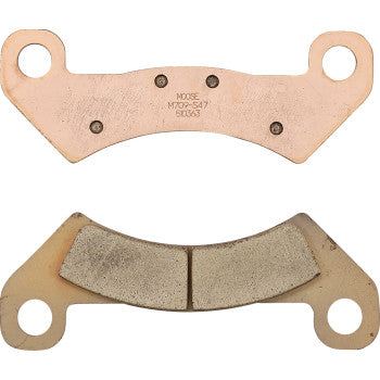 The John Deere Brake Pad Front by Moose Offroad is shown in two styles: one with a smooth surface and dual holes, the other with segmented friction material for even braking and matching mounting holes.