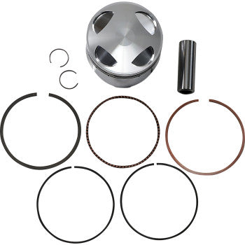 Polished silver metal piston with cutouts, pin, circlips, and five black and bronze piston rings arranged below.