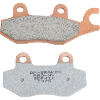 Two Pro MX Sintered Brake Pads by DP Brakes feature copper-colored backing plates—one displays the sintered metal friction surface, while the other shows stamped product info, delivering peak braking performance for demanding riders.