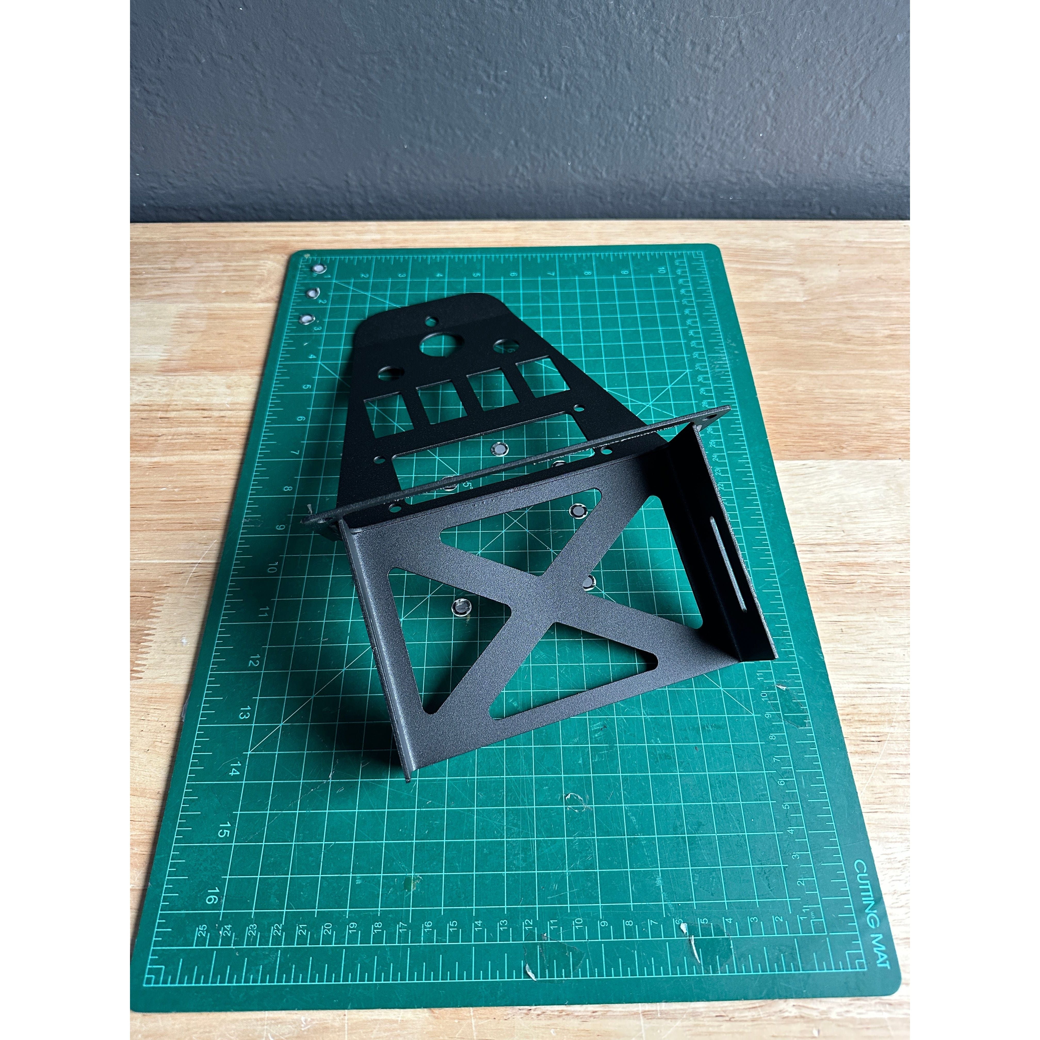 A Short Polaris ProR/XP PCI Kenwood +4 by StayFlush, featuring a black factory switch mount with geometric cutouts, sits on a green cutting mat atop a wooden surface against a textured dark gray wall.