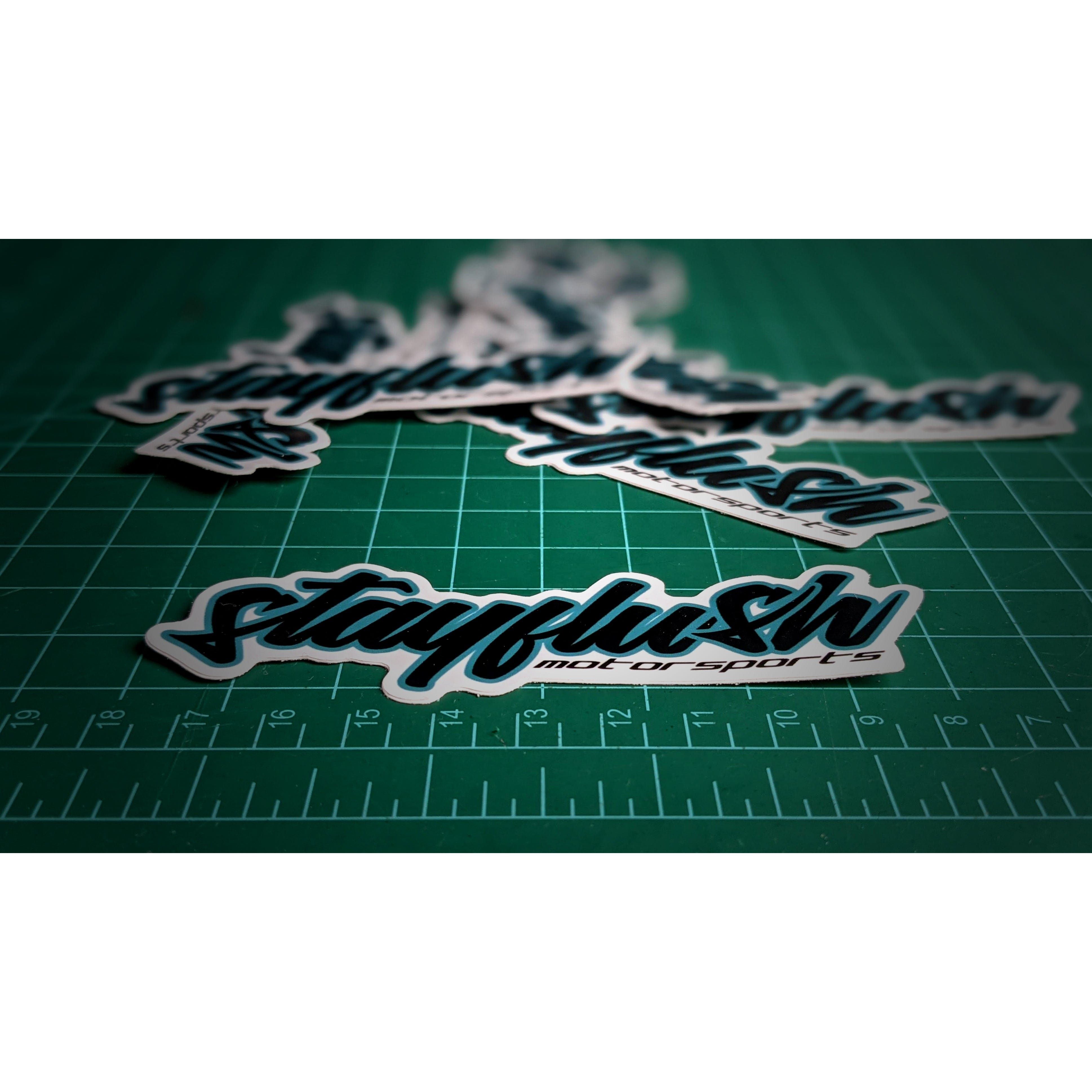 Several Stickers by StayFlush in bold script font are scattered on a green cutting mat with measurement lines, highlighting the premium 4x1.35 stickers in the front and their high quality coating.
