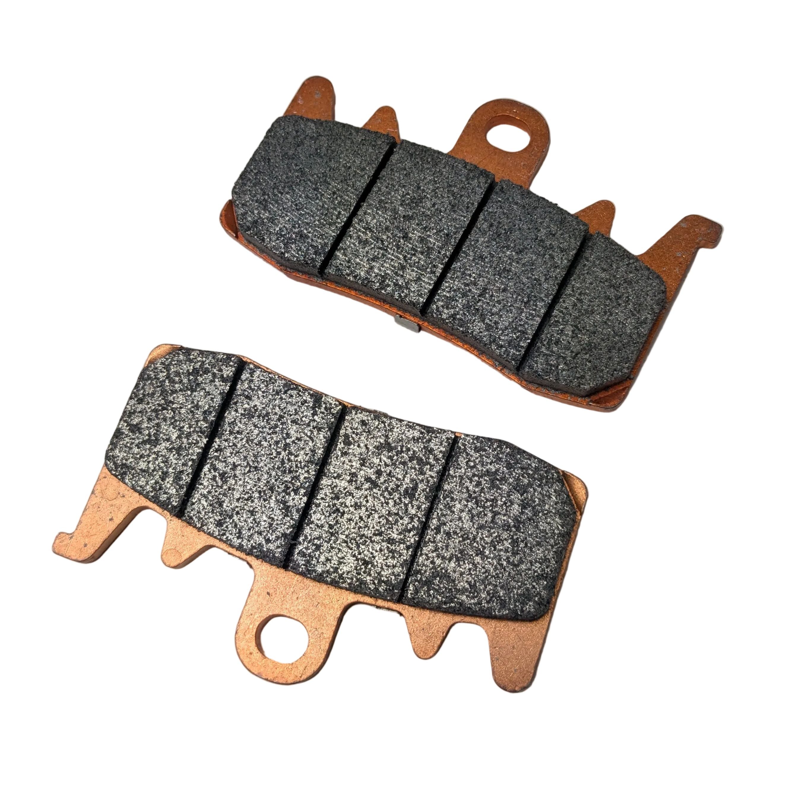 Two copper-backed brake pads with textured grey friction surfaces and mounting holes for Indian motorcycles.