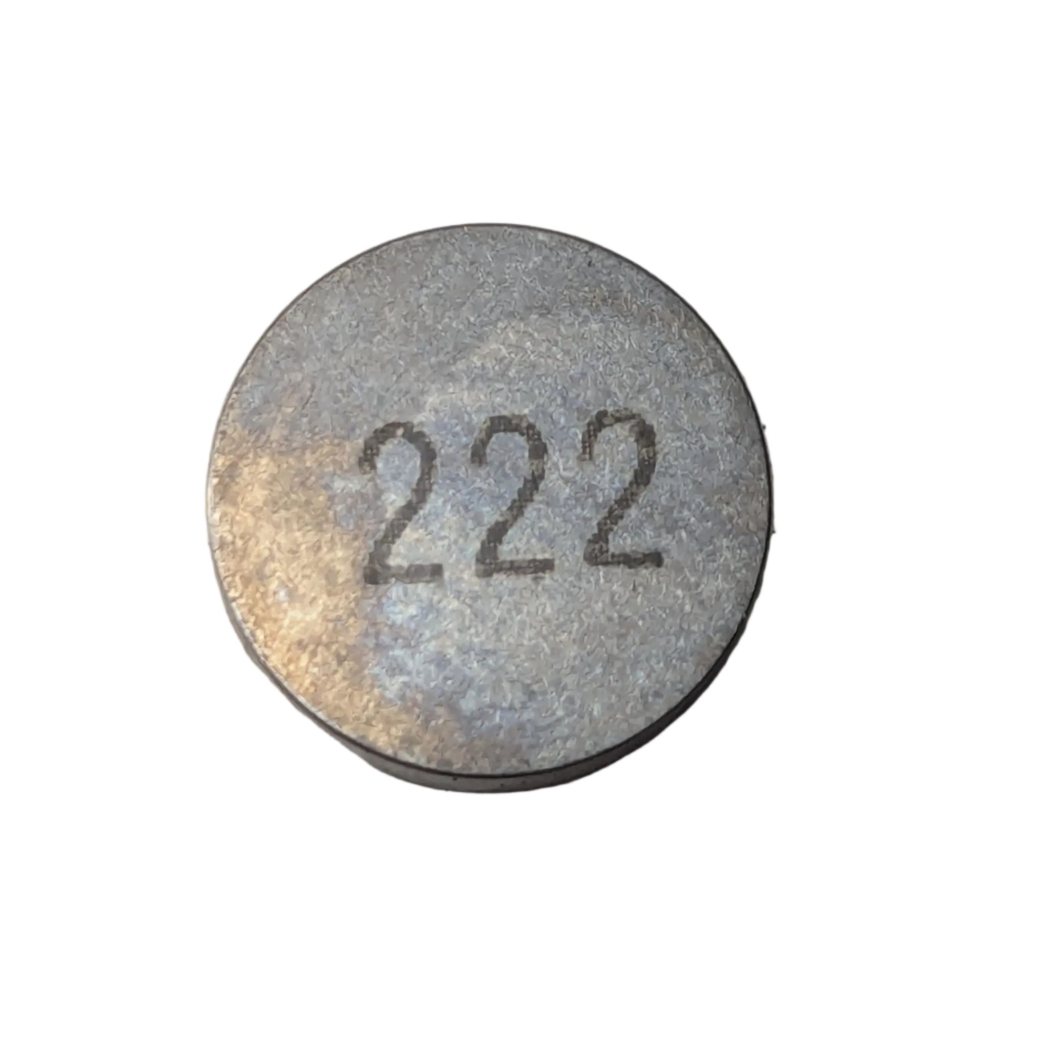 Round silver metal valve lash shim with "222" engraved on the flat top surface.