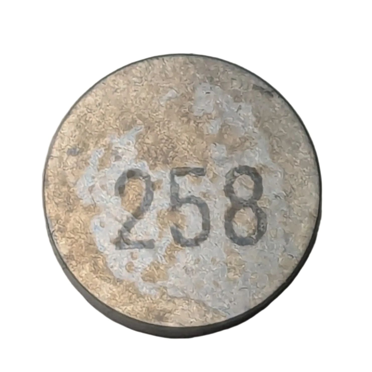 Round metallic shim valve with worn silver surface and engraved number 258 on top.