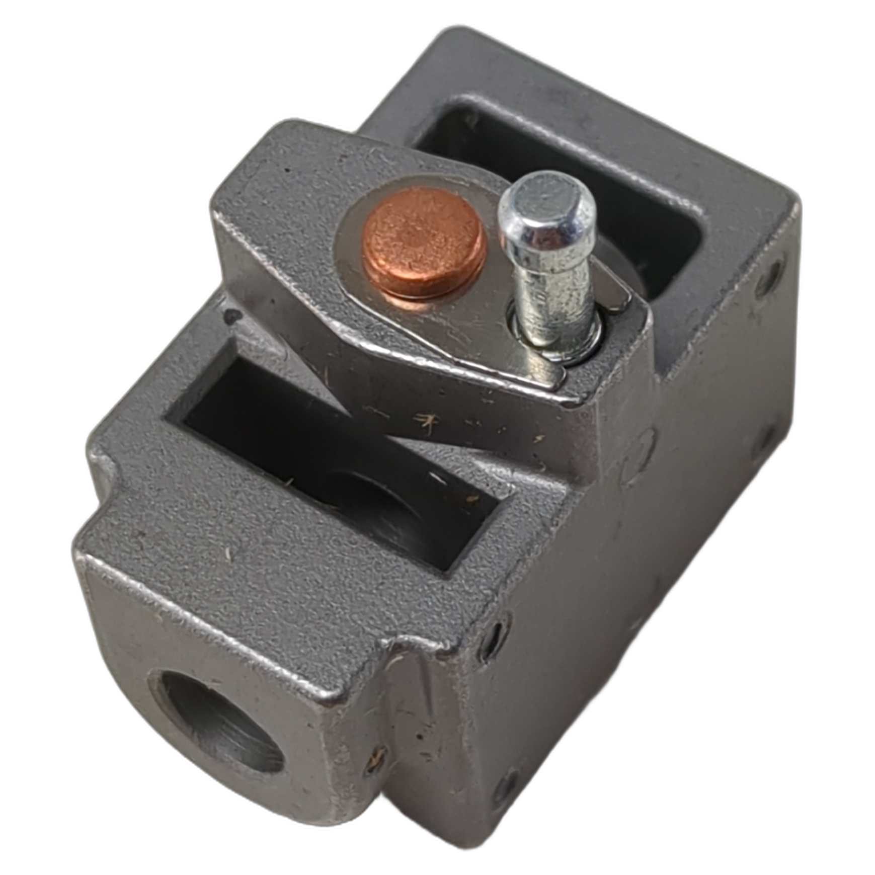 Gray metal shift fork block with cylindrical pin and copper-colored circular component.