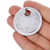 A hand holds the Spark Plug Gap Tool by Witchdoctors, a round metal tool with engraved inch and millimeter markings along the edges and a large hole near the top.