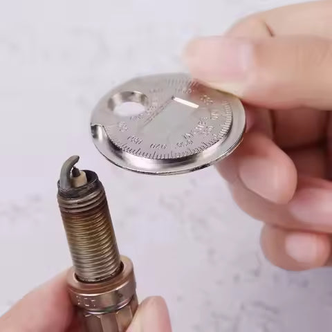 A person uses the Spark Plug Gap Tool by Witchdoctors to accurately measure the gap on a spark plugs electrode.