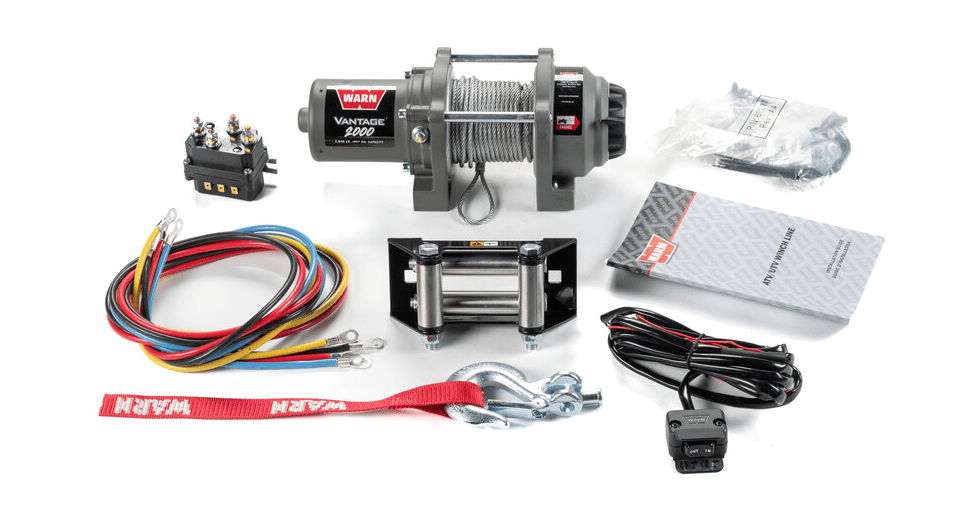 A 2000 lb. Vantage 2000 Winch with wire rope by Warn, including control box, colored wires, roller fairlead, hook with red WARN strap, remote control, hardware, and manual displayed on a white background.