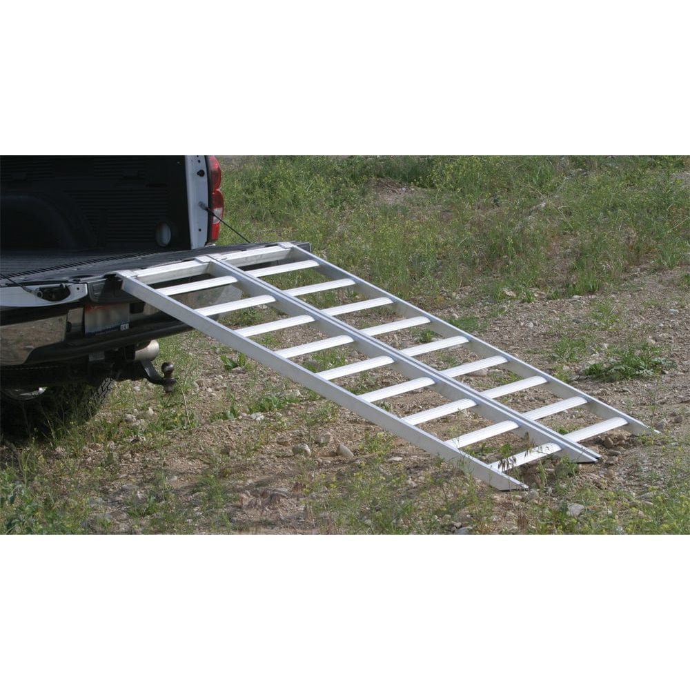 The Aluminum Folding Ramp 1500 Lbs 84 X 48 by Open Trail extends from a pickup trucks open tailgate to the ground, set on an outdoor area of dirt and grass.
