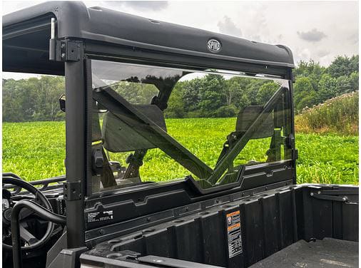 Close-up of the rear window and cargo bed on a black Polaris Ranger 1000 with a Spike Rear Windshield, parked in a green field under cloudy skies, offering enhanced riding enjoyment for your off-road adventures.