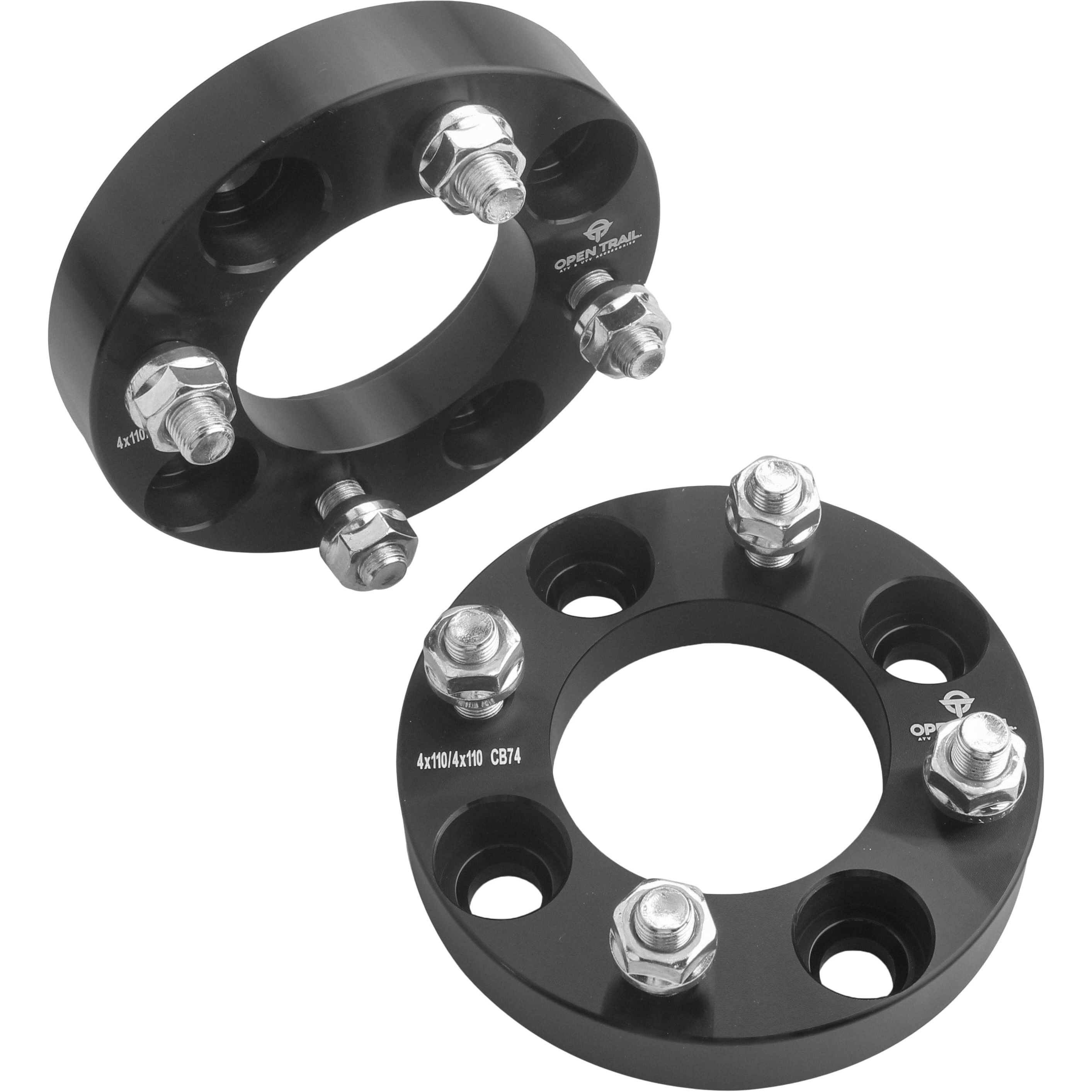 Two black Open Trail Wheel Spacer 1 4/110 spacers, each with four 10mm x 1.25mm studs and nuts, are shown. These spacers fit vehicle wheel hubs to enhance traction and stability.