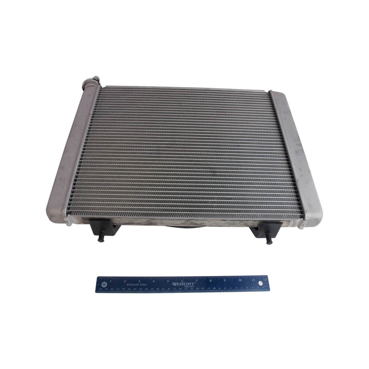 Rectangular metal Polaris radiator with horizontal cooling fins and black connectors, shown with blue ruler for scale.