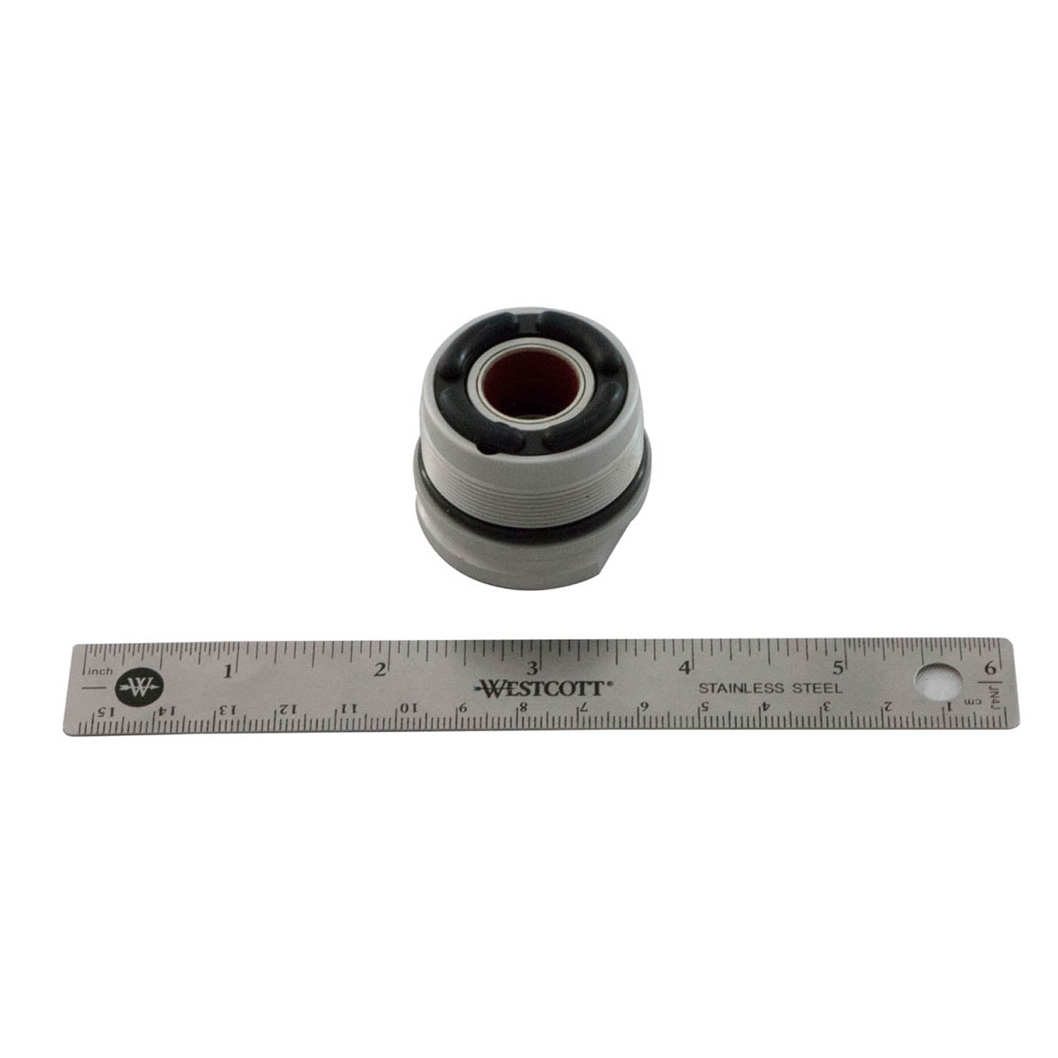 Small cylindrical metal bearing with black rubber seal on both ends, placed above a 12-inch stainless steel ruler.