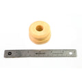 Beige cylindrical rubber bump stop with a central hole, shown next to a 6-inch metal ruler for scale.