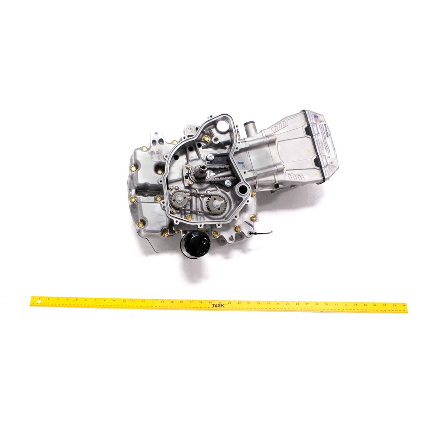 Metallic long block engine kit with aluminum casing and exposed mechanical components, shown with yellow measuring tape.