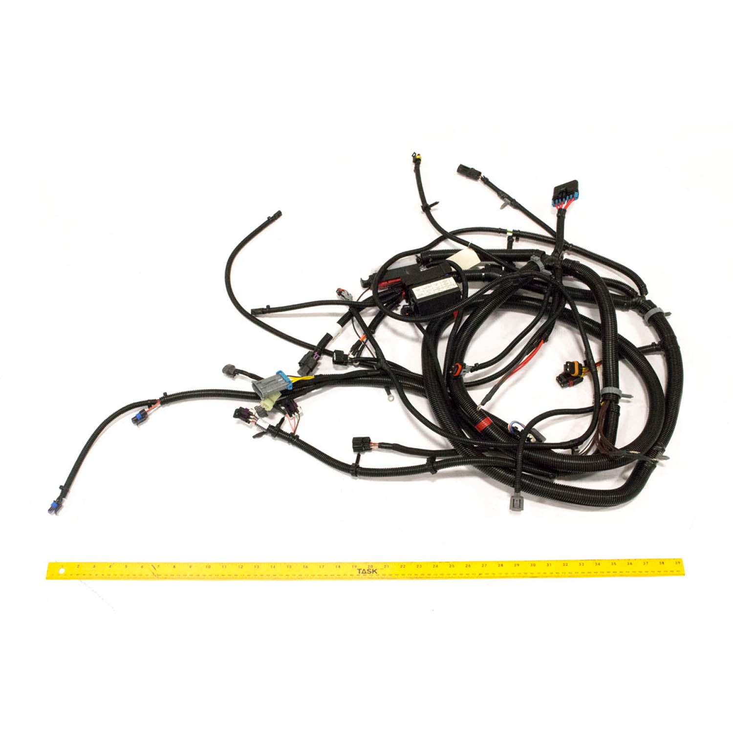 Black bundled chassis harness wiring with multiple connectors and protective tubing, laid beside a yellow measuring ruler.