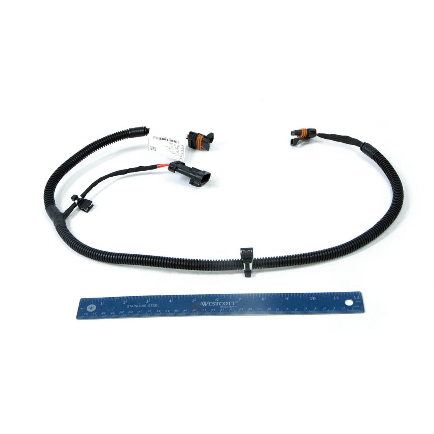 Black flexible wiring harness with connectors and clips, shown next to a blue ruler for scale.