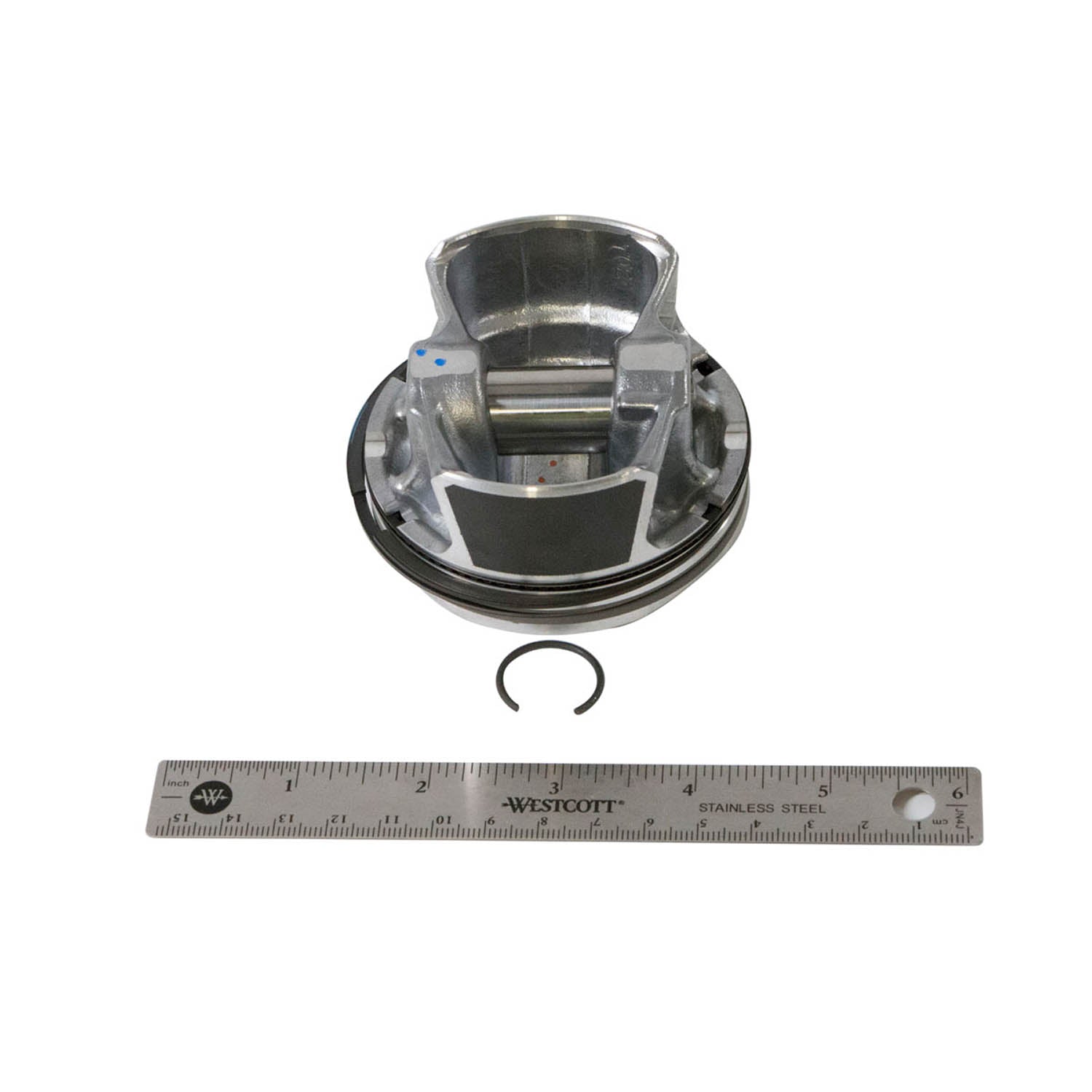 Silver metallic 78 mm piston with grooves, matching circular clip, and 6-inch metal ruler for scale.