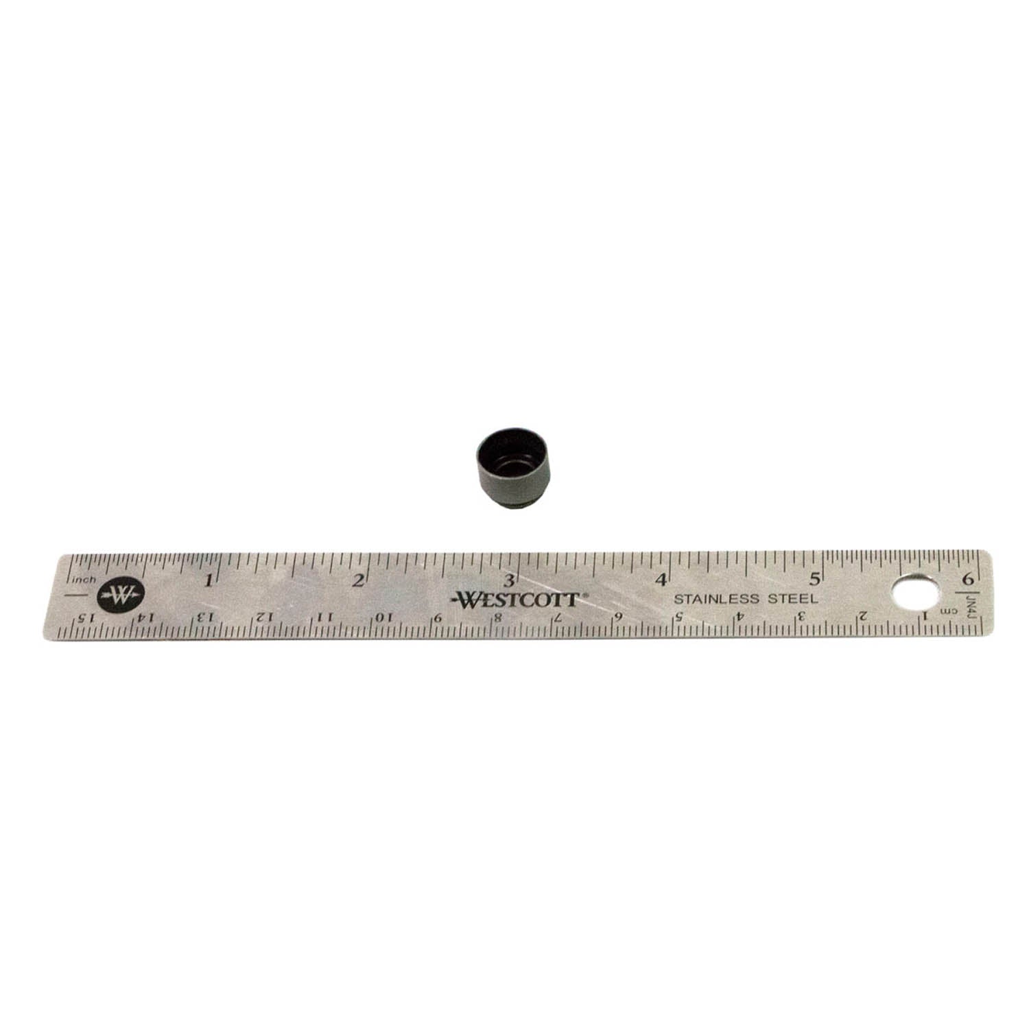 Small black rubber and metal valve stem seal next to a 6-inch metal ruler for size reference.