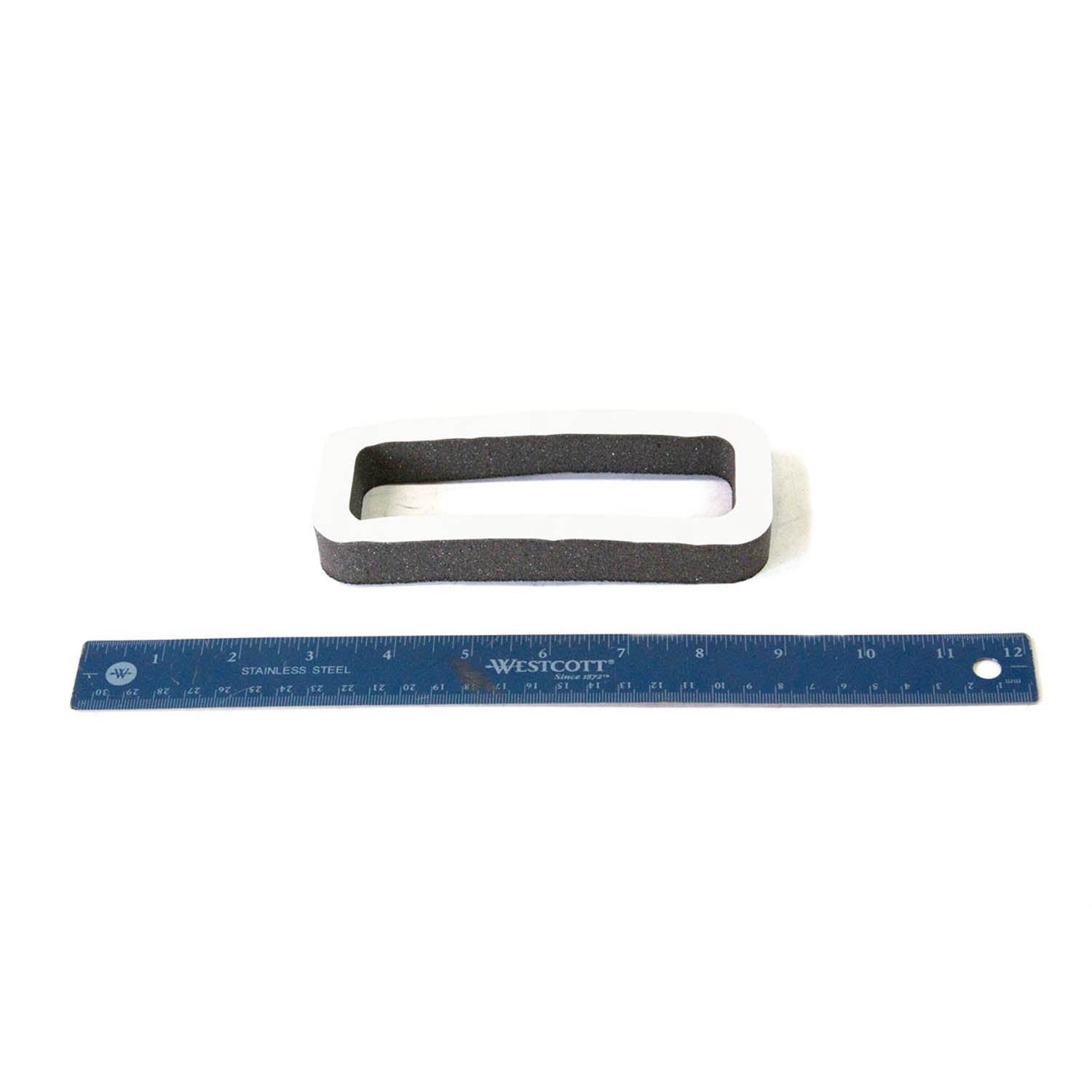 Black rectangular rubber center dash seal with white plastic frame, shown next to a blue 12-inch ruler for scale.