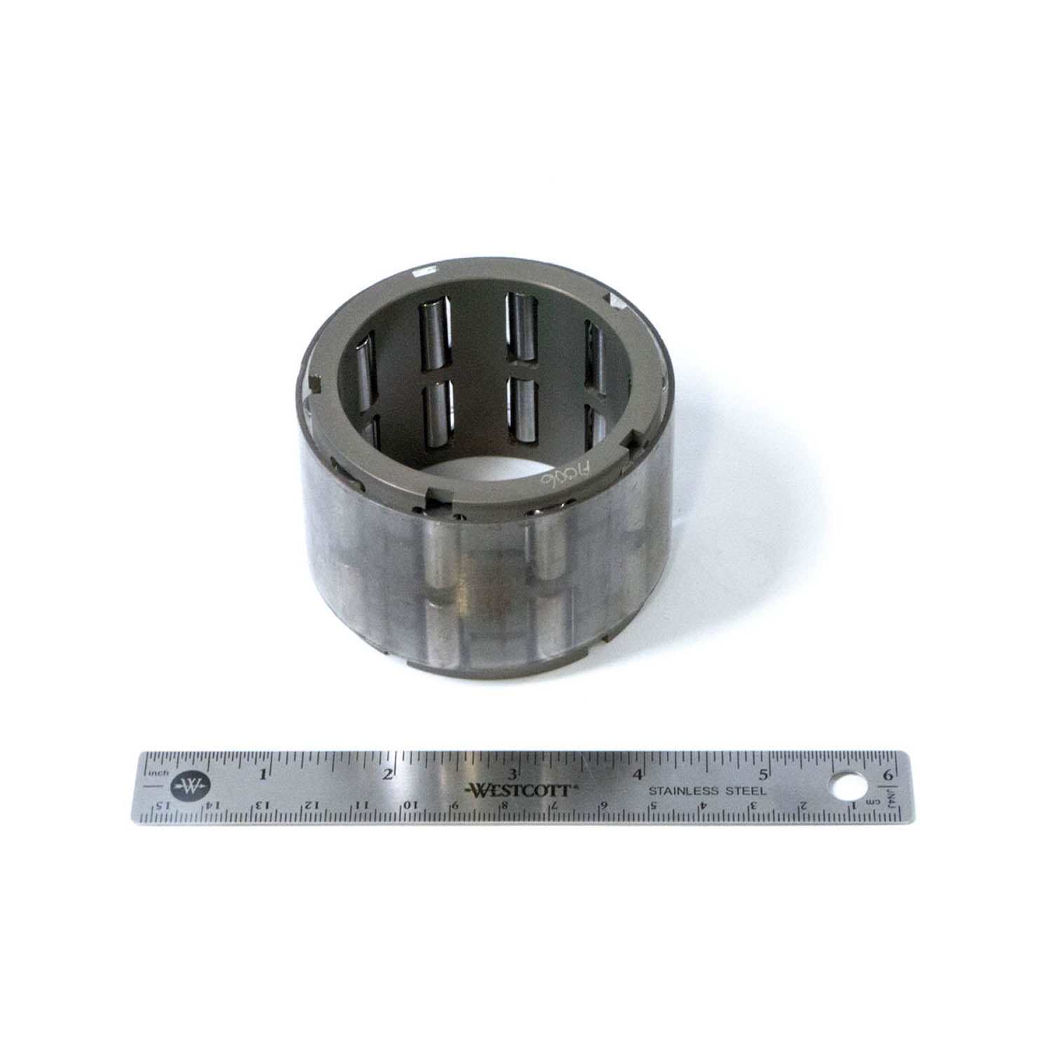 Cylindrical metal roller cage bearing with evenly spaced rollers, shown next to 12-inch ruler for size reference.