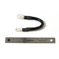 Black short battery cable with metal loop terminals on both ends and heat shrink tubing, shown next to a ruler for scale.