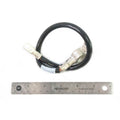 Black insulated battery to ground cable with metal terminal connectors on each end, shown with a metal ruler for scale.