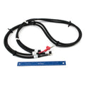 Black cable assembly with red and black terminal connectors and attached white labels next to a blue ruler.