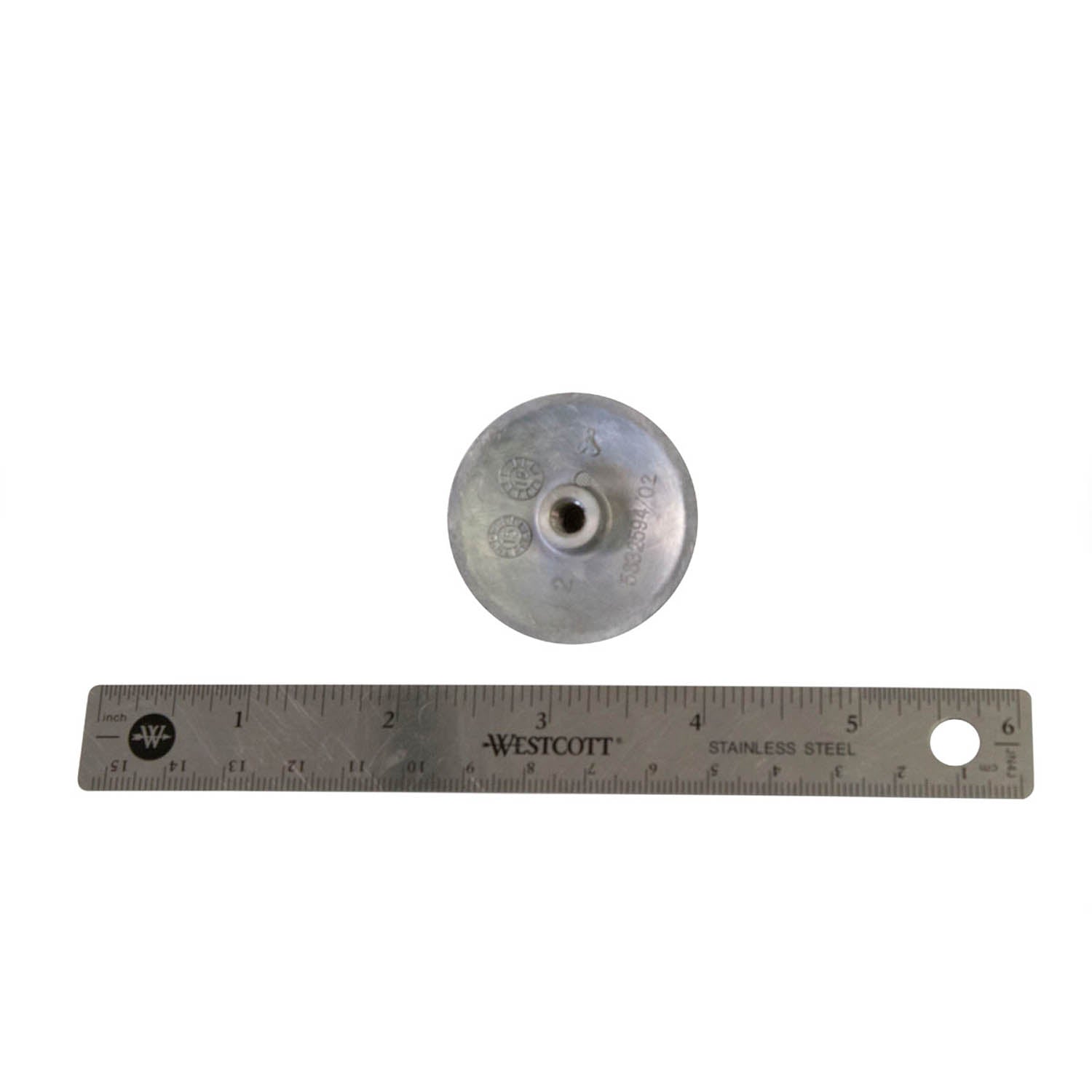 Silver metal water pump impeller with central hole, placed above a 12-inch metal ruler showing size.