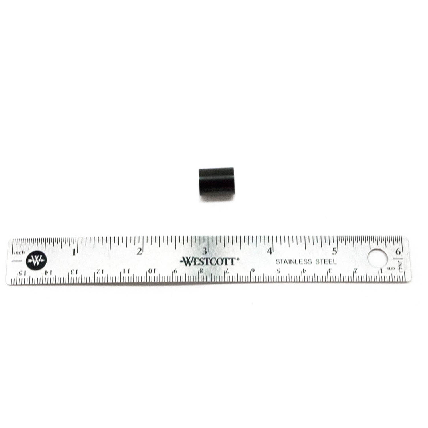 Small black cylindrical oil pump piston placed above a 12-inch silver metal ruler with black markings.