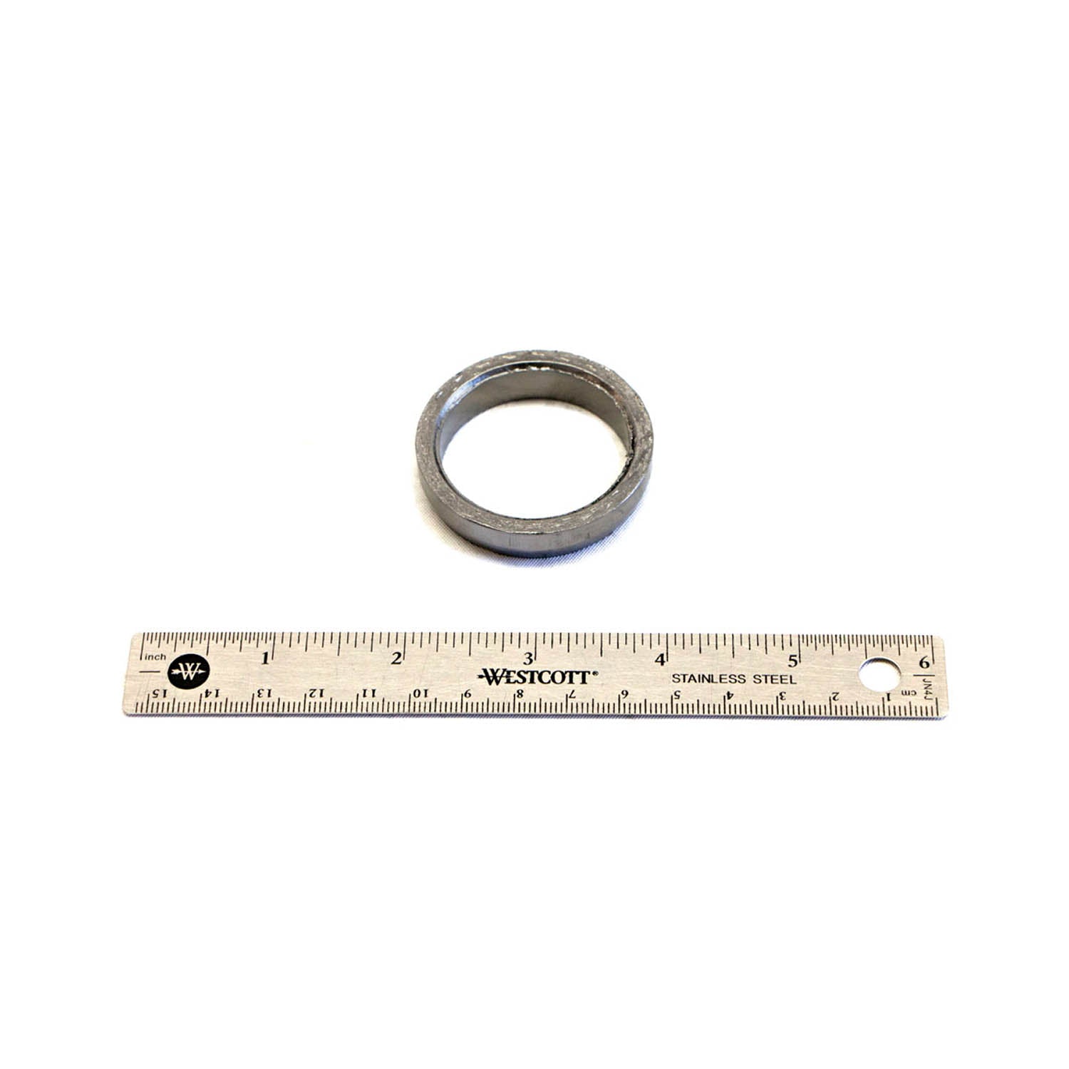 Metallic circular exhaust gasket with a slightly textured surface next to a 12-inch ruler for size reference.