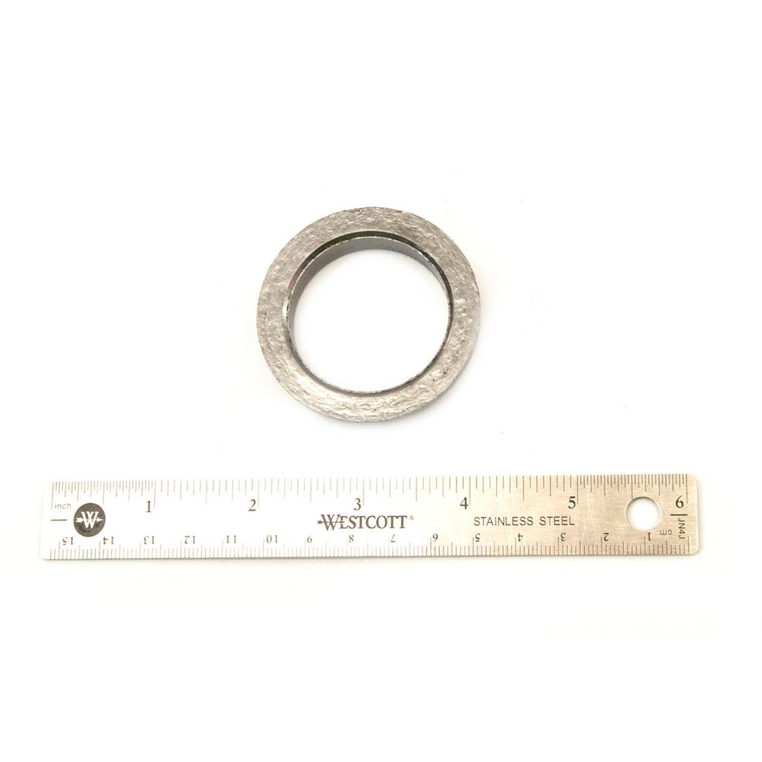 Round metallic exhaust gasket with a textured surface next to a 6-inch stainless steel ruler.