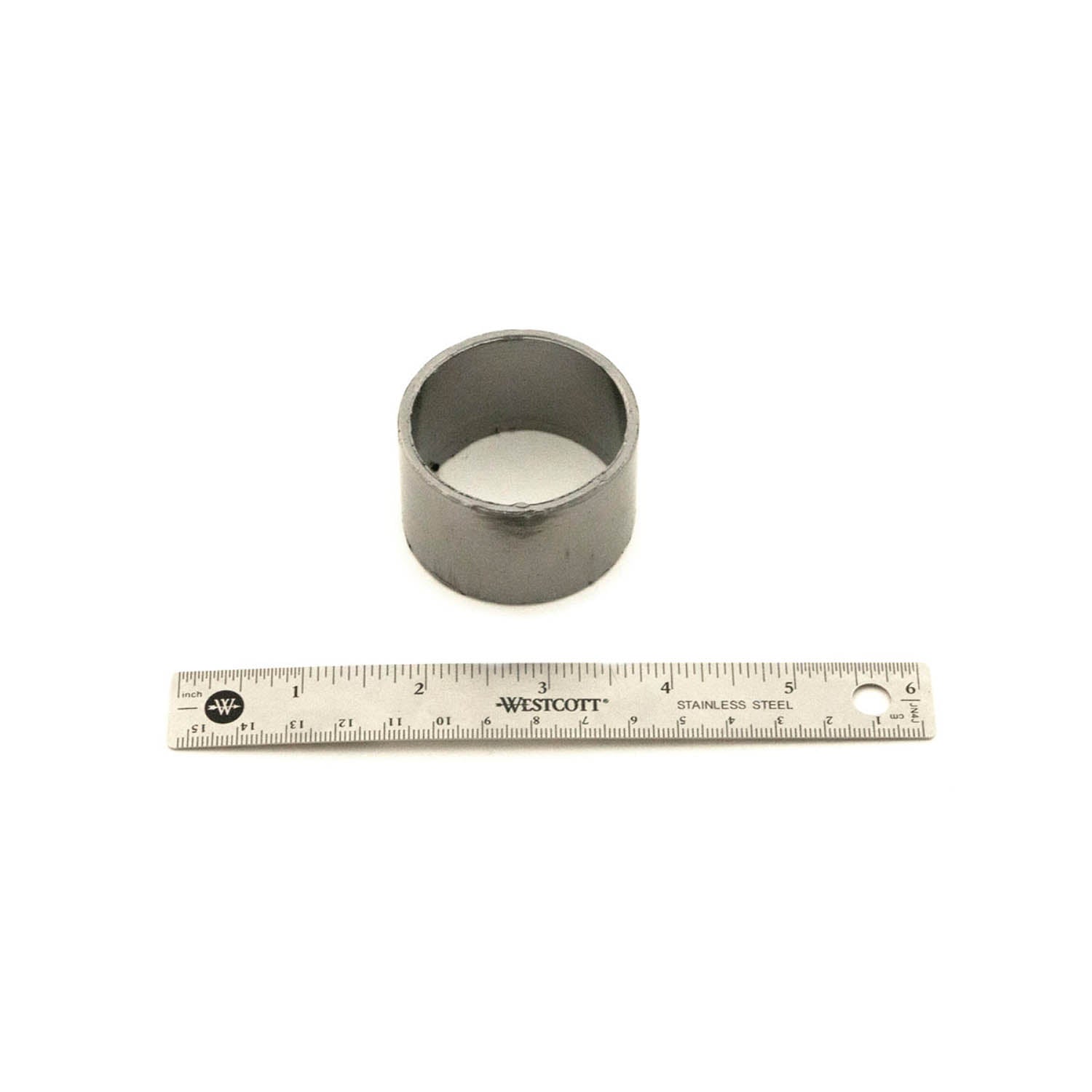 Silver cylindrical metal exhaust gasket with smooth surface next to a 6-inch ruler for scale.