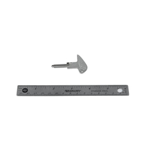 Silver metal motorcycle key blank with triangular bow and uncut blade next to a 6-inch ruler.
