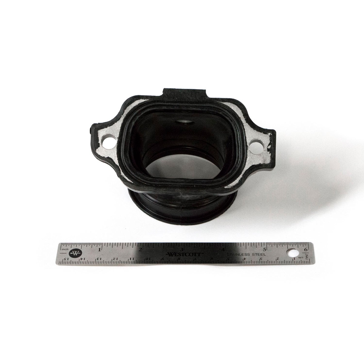 Black rubber and metal throttle body adapter with mounting holes, shown next to a metal ruler for scale.