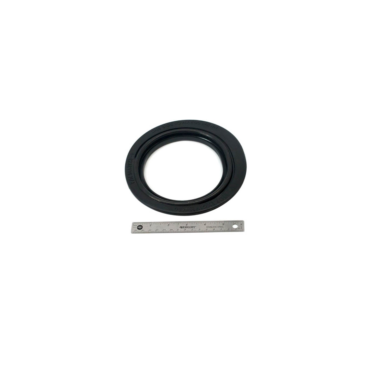 Black rubber inner clutch cover seal with circular shape and grooved edges next to a ruler for scale.