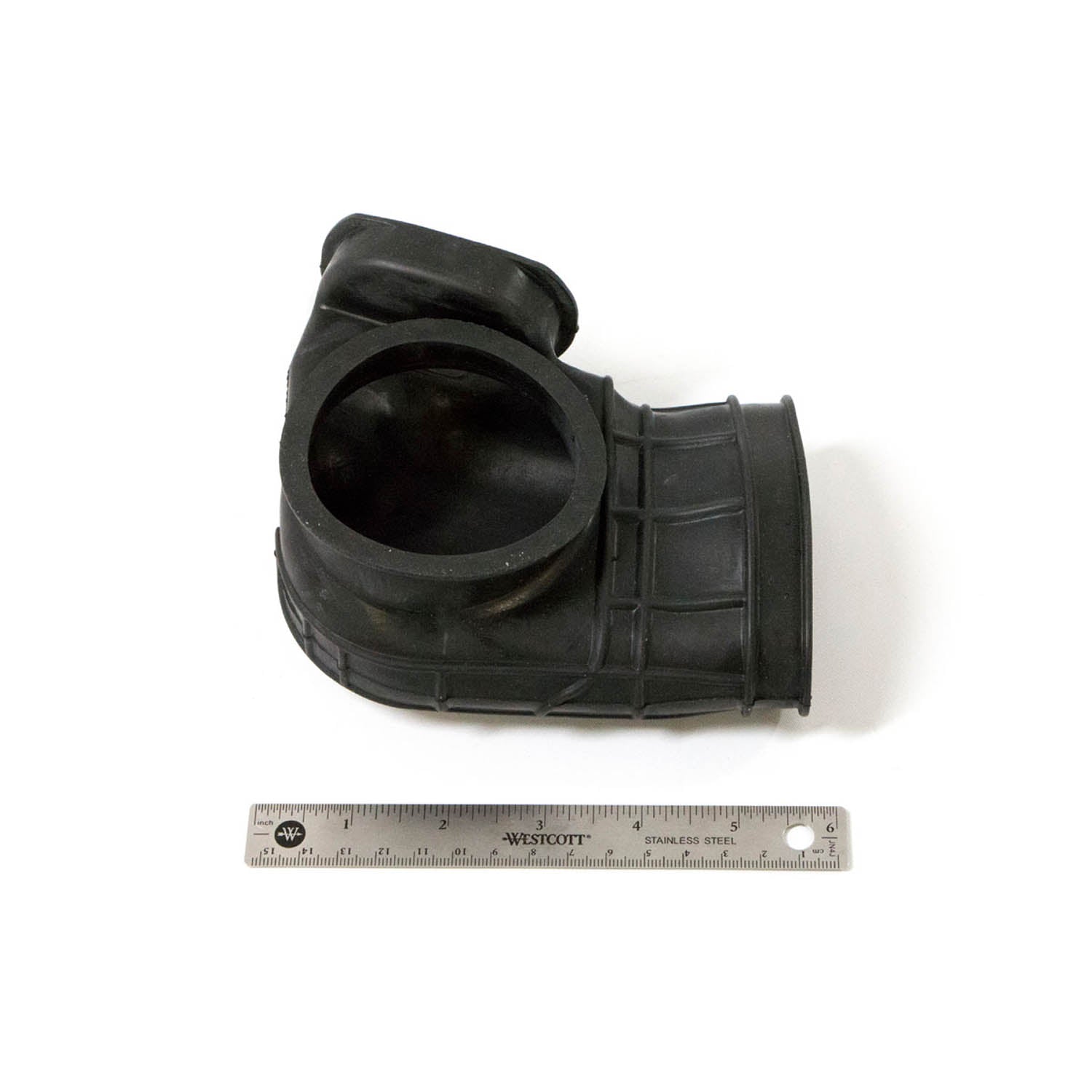 Black rubber clutch boot inlet with ribbed texture and circular openings next to a metal ruler for scale.