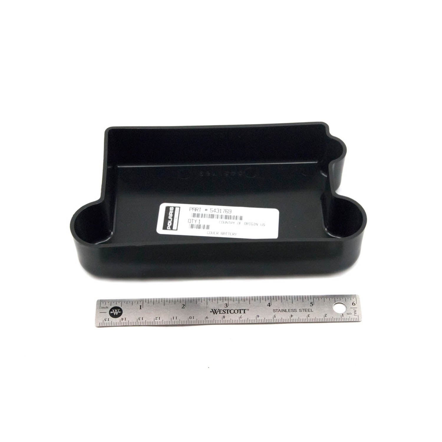 Black rectangular plastic battery cover with rounded edges and a label on top, shown next to a metal ruler for scale.