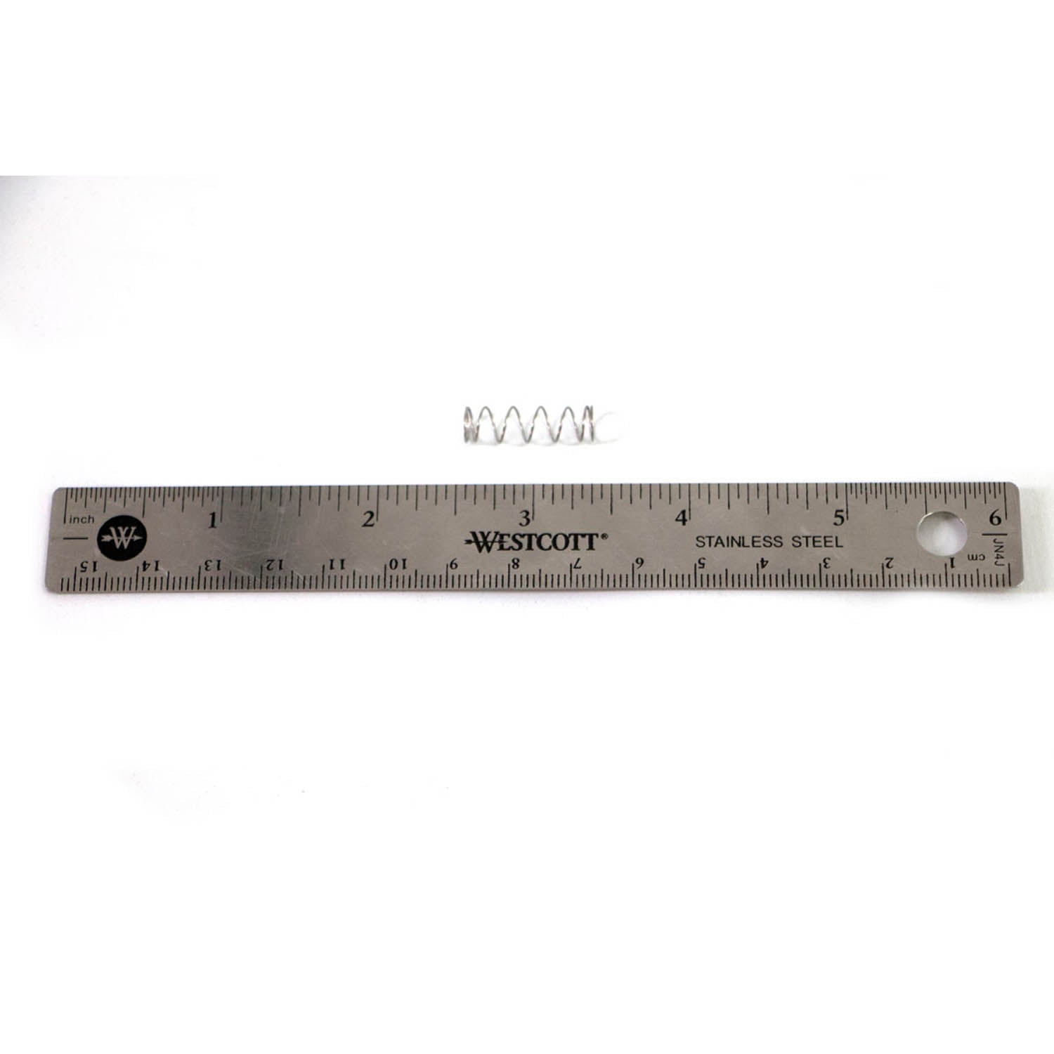 Small coiled metal spring placed above a 12-inch stainless steel ruler with black measurement markings.