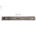 Small coiled metal spring placed above a 12-inch stainless steel ruler with black measurement markings.
